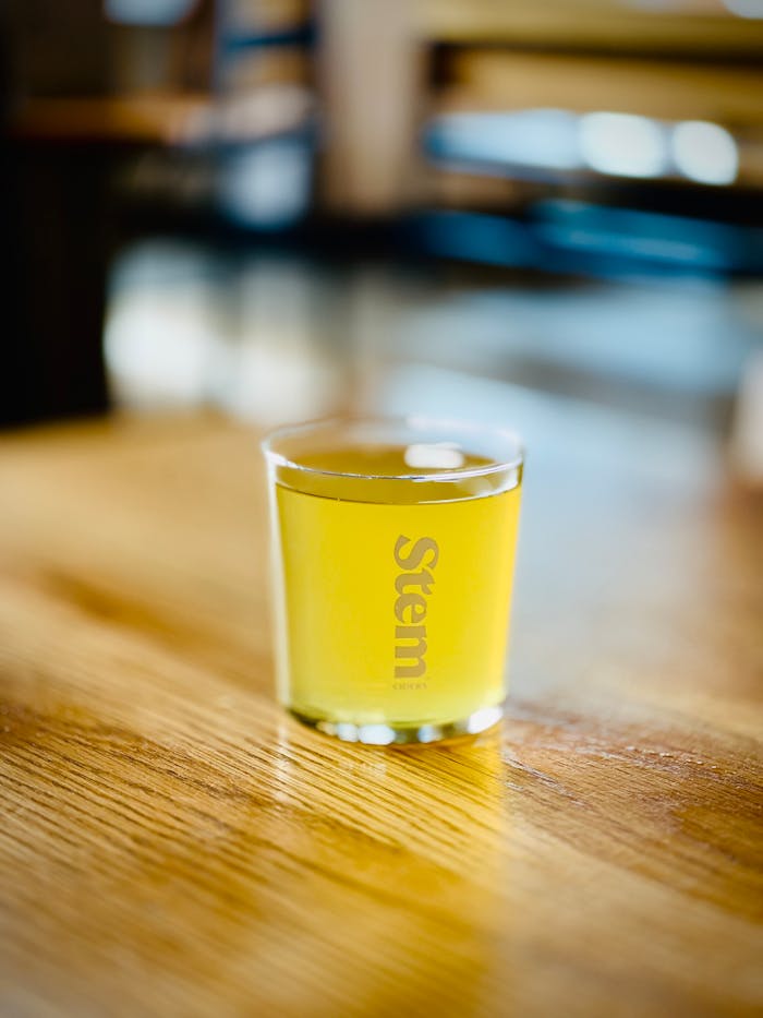 Close-up of a refreshing glass of cider on a wooden table in a cozy indoor setting.